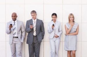 Group of business associates in a line text messaging on their cellphone